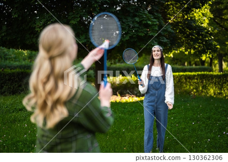 Friends enjoying a sunny day playing badminton in a vibrant green park Friends enjoying a sunny day playing badminton in a vibrant green park 130362306