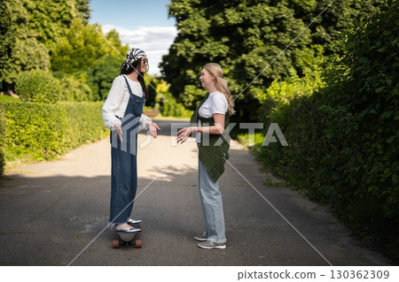 Friends enjoying a sunny day while practicing skateboarding tricks outdoors Friends enjoying a sunny day while practicing skateboarding tricks outdoors 130362309