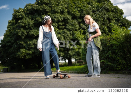 Friends enjoy a sunny day practicing skateboarding tricks in the park Friends enjoy a sunny day practicing skateboarding tricks in the park 130362338