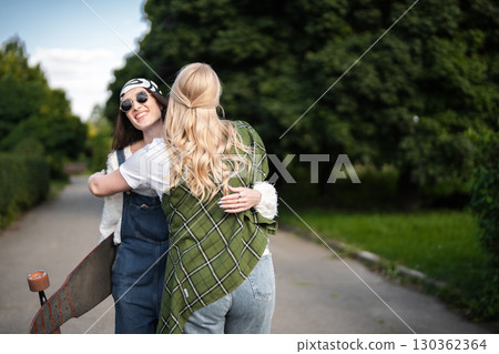 Friends joyfully reunite in a sunlit park during a warm afternoon 130362364