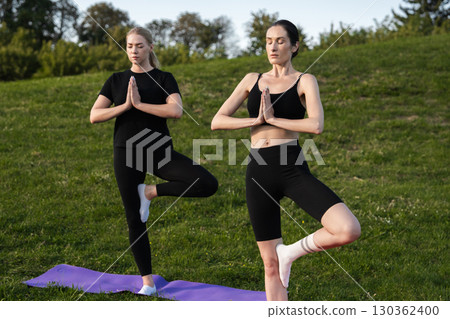Practicing yoga in the park during a sunny afternoon with friends 130362400