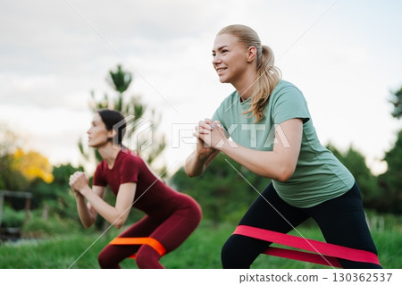 Women exercising outdoors with resistance bands during a sunny day 130362537
