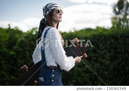 Stylish young woman skateboarding in a lush green urban area Stylish young woman skateboarding in a lush green urban area 130362549