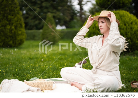 Woman enjoying a peaceful picnic on a sunny day in a lush green park 130362570