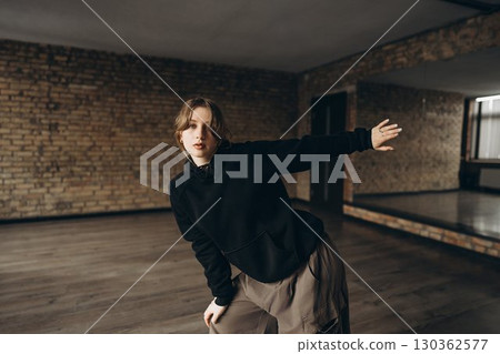 Young dancer practicing in an urban studio with exposed brick walls 130362577