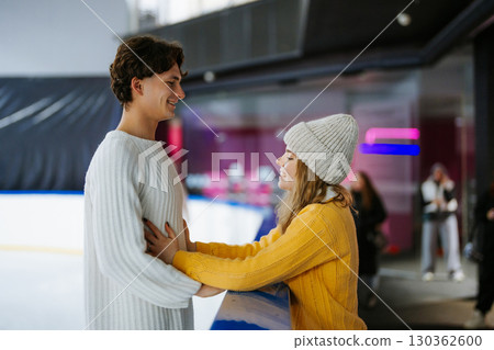 Young couple enjoys ice skating and each others company at rink 130362600