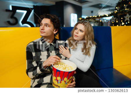 Couple enjoying popcorn while waiting for a movie in a cinema hall 130362613