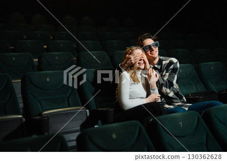 Couple enjoying a movie together in a dark theater with empty seats Couple enjoying a movie together in a dark theater with empty seats 130362628
