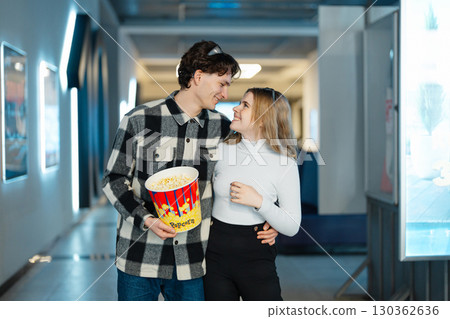 Young couple enjoys a fun outing at the cinema with popcorn in hand Young couple enjoys a fun outing at the cinema with popcorn in hand 130362636