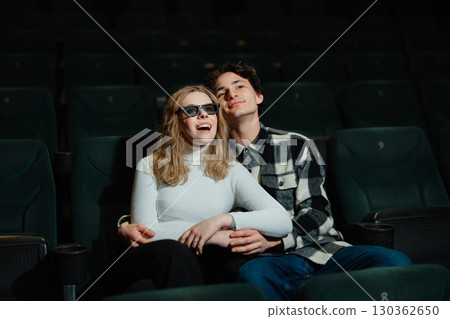 Couple enjoying a movie together in a quiet theater setting 130362650