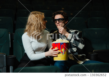 Couple enjoying a movie together with popcorn in a theater 130362652