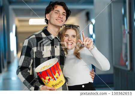 Young couple enjoying popcorn while posing for a cheerful moment at the cinema 130362653