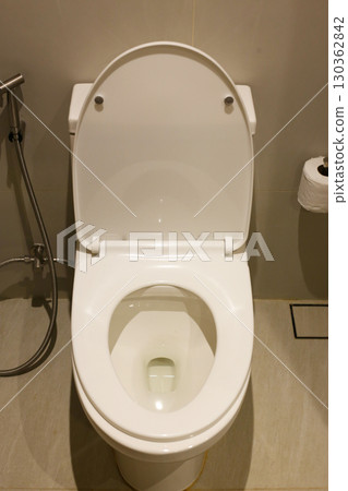 A modern white ceramic toilet with the lid closed, installed in a tiled bathroom 130362842