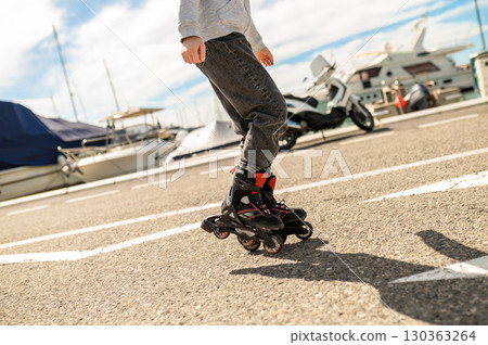 Unrecognizable girl resting on rollerblades at marina near yachts enjoying sunny outdoor day Unrecognizable girl resting on rollerblades at marina near yachts enjoying sunny outdoor day 130363264