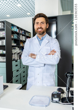 Dark-haired bearded pharmacist in a lab coat looking confident and contented 130363555