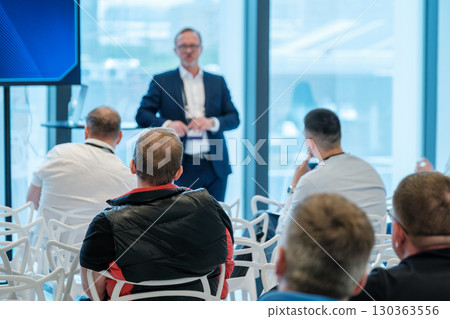 Speaker presenting to audience in a modern well-lit conference space 130363556