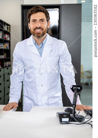 Caucasian man in lab coat standing at the counter in the pharmacy Caucasian man in lab coat standing at the counter in the pharmacy 130363582