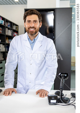 Caucasian man in lab coat standing at the counter in the pharmacy 130363583