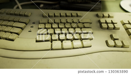 Dust accumulates on a once vibrant computer keyboard, capturing a moment of neglect in a cluttered workspace. Memories of typing and communication linger in the air. 130363890