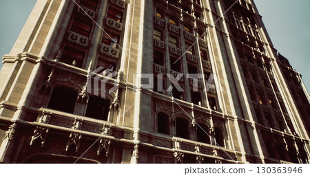 A magnificent building features detailed stonework and architectural elegance, illuminated by bright sunlight. The structure stands tall against a clear sky, capturing attention with its grandeur. 130363946