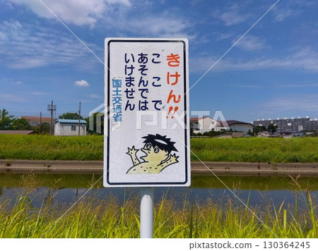 Summer floodway scene with a water safety sign Summer floodway scene with a water safety sign 130364245