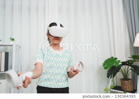 A young girl experiencing the metaverse, using a futuristic VR headset for entertainment at home. A young girl experiencing the metaverse, using a futuristic VR headset for entertainment at home. 130364393