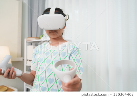 Young girl experiences metaverse using futuristic VR headset for home entertainment. 130364402