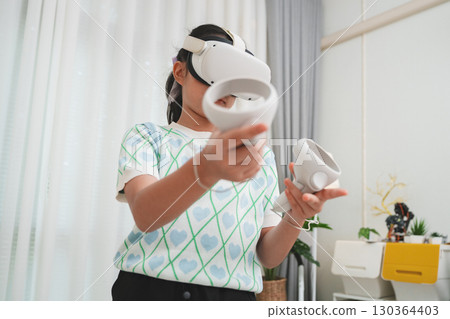 Young student uses VR headset for interactive lesson, transforming education. Future of virtual learning and immersive EdTech at home. 130364403