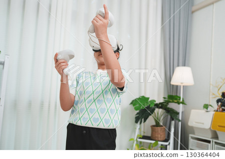 Elementary school kid's virtual reality experience. Child with VR goggles plays 3D simulation game. Elementary school kid's virtual reality experience. Child with VR goggles plays 3D simulation game. 130364404