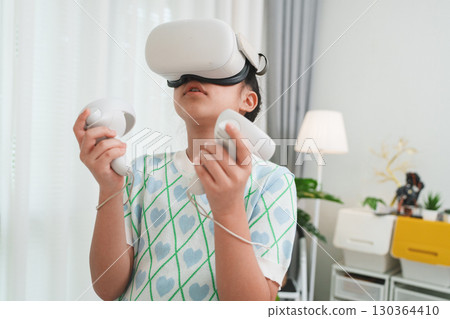 Girl exploring metaverse with VR goggles for virtual learning and simulation. 130364410