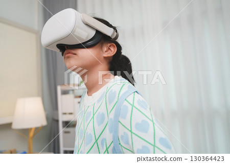 Asian girl amazed by VR headset experience. Immersive edutainment simulation. Asian girl amazed by VR headset experience. Immersive edutainment simulation. 130364423