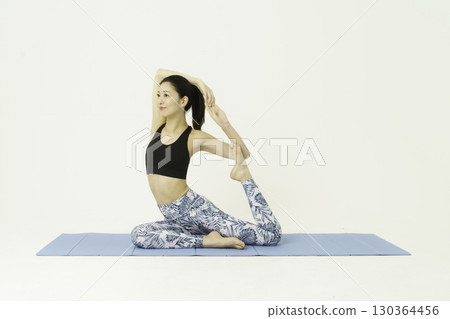 Young woman doing pigeon pose yoga on white background 130364456