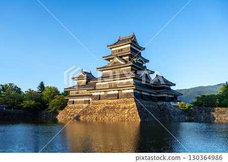 Matsumoto Castle reflecting in the water at sunset, Japan 130364986