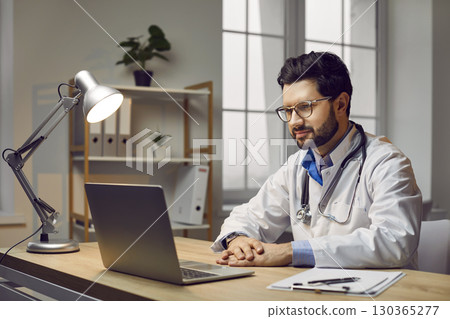 Male doctor making online video call consulting patient using laptop 130365277