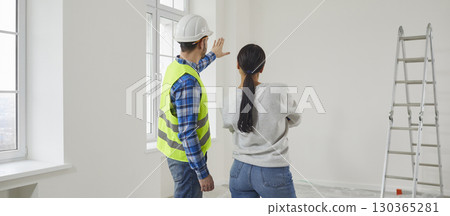 Professional repairman explaining future home design plan to young woman Professional repairman explaining future home design plan to young woman 130365281