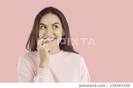 Happy woman standing on pink background, looking to copy space side, thinking and smiling Happy woman standing on pink background, looking to copy space side, thinking and smiling 130365299