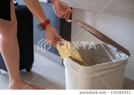 Close up of Asian woman hand putting waste into trash can highlighting proper waste disposal Close up of Asian woman hand putting waste into trash can highlighting proper waste disposal 130365451