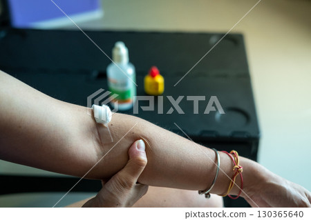 Medical care concept cotton swab pressed on injection wound on Asian woman arm in clinic 130365640