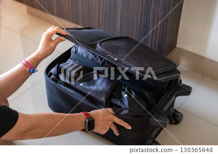 Woman hands neatly packing suitcase with clothes and travel essentials for holiday vacation trip 130365648
