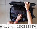 Female hands arranging clothing in open suitcase symbolizing travel preparation and  130365650