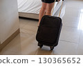 Asian woman dragging suitcase across hotel room floor symbolizing travel, tourism, and vacation 130365652