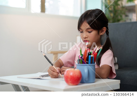 Back to School. Young girl studying at home with school supplies and apple. 130366414