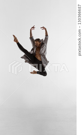 Male performer leaping high in coat with strong leg extension and focused emotional power Male performer leaping high in coat with strong leg extension and focused emotional power 130366687