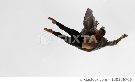 Male dancer floating horizontally in coat with focused gaze and emotional restraint 130366706