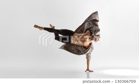 Male dancer balancing on one arm in coat with extended legs and emotional strength Male dancer balancing on one arm in coat with extended legs and emotional strength 130366709
