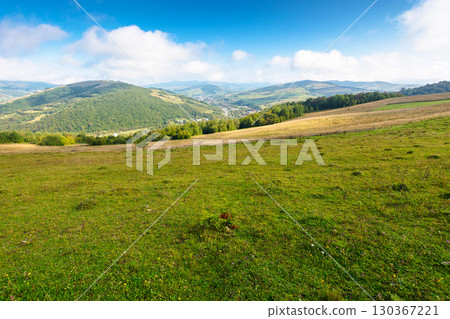 scenery with rural field on grassy hill of mountains. beautiful countryside landscape in ukrainian carpathians on a sunny day. scenic view of alpine pasture and distant valley. forest on hillside scenery with rural field on grassy hill of mountains. beautiful countryside landscape in ukrainian carpathians on a sunny day. scenic view of alpine pasture and distant valley. forest on hillside 130367221
