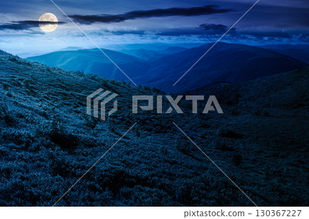 mountain landscape in summer at night. beautiful view of rolling green hills and alpine meadows in full moon light. scenery with clouds on the dark sky. scenic nature background for travel 130367227