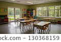 A cozy, empty elementary school classroom with wooden desks, large windows, and children's drawings on the walls, bathed in natural daylight. The concept of the beginning of the school year. 130368159