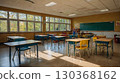 A cozy, empty elementary school classroom with wooden desks, large windows, and children's drawings on the walls, bathed in natural daylight. The concept of the beginning of the school year. 130368162