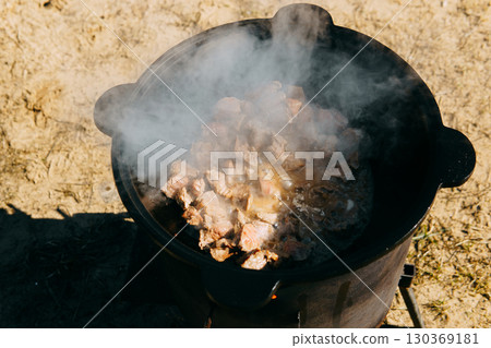 Meat cooking in cauldron outdoor. Plov recipe with meat. Cooking food street. Traditional cuisine and oriental dish. Meat cooking in cauldron outdoor. Plov recipe with meat. Cooking food street. Traditional cuisine and oriental dish. 130369181